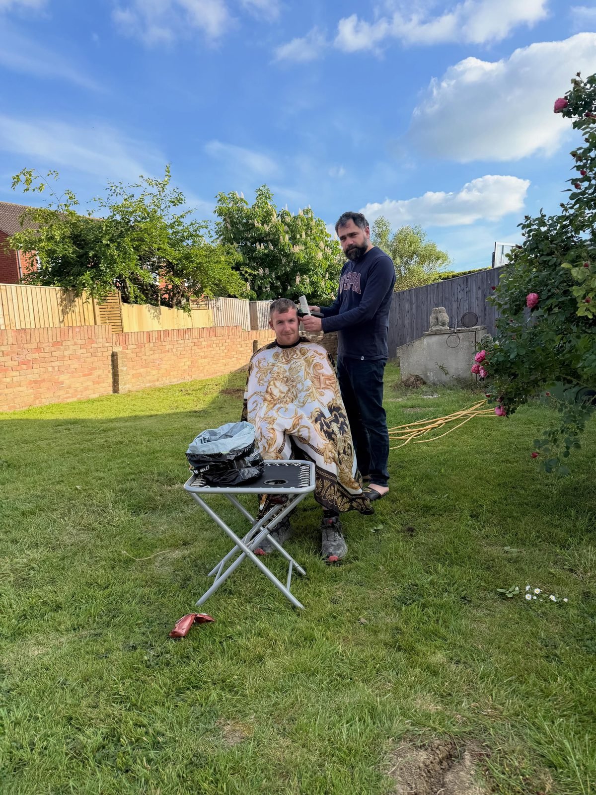 Pasha giving a client a haircut in a garden setting